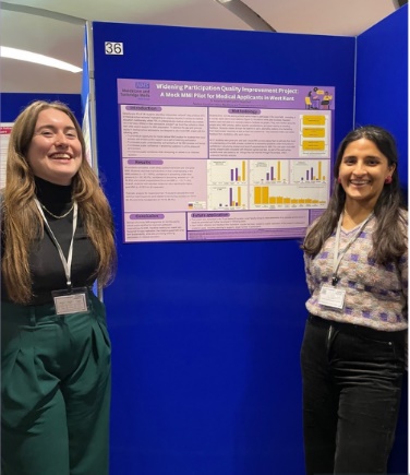 2 people standing by a poster